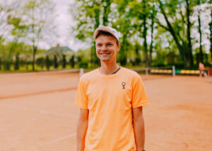 Wojtek Jobczyk uśmiecha się na korcie tenisowym
